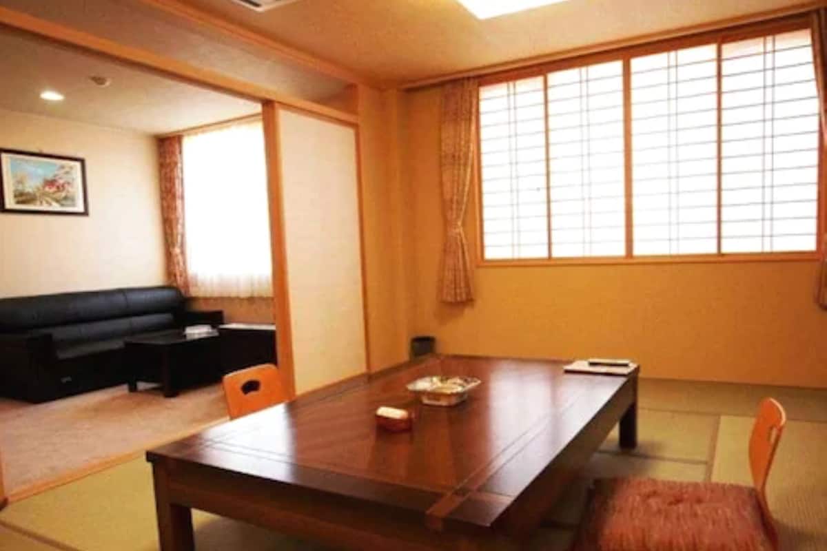 A traditional Japanese-style room with tatami flooring, a low table, and a sofa.