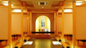 Un couloir d’hôtel avec des bancs en bois, une allée centrale et une grande fenêtre en arc de cercle.