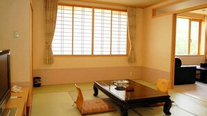 Une pièce de style japonais traditionnel, avec un sol recouvert de tatamis, une table basse et des portes coulissantes.