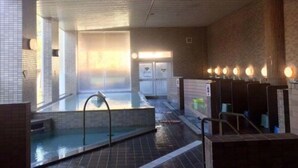 Un espace de bien-être comprenant un jacuzzi, des murs carrelés et une rangée d’éviers.