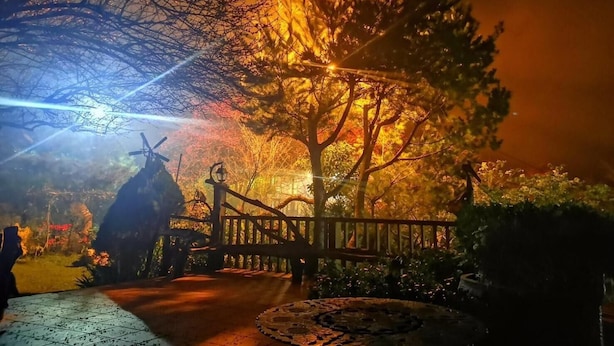 A nighttime outdoor area with a wooden fence, a windmill, and a paved walkway. - Shanlin Songjing Leisure Farm (Nanzhuang)