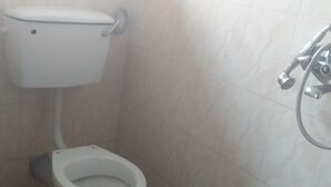 A bathroom with a toilet and a shower. - Elite Lodge (Ntungamo)