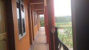 A corridor with windows and a view of a green landscape. - Elite Lodge (Ntungamo)