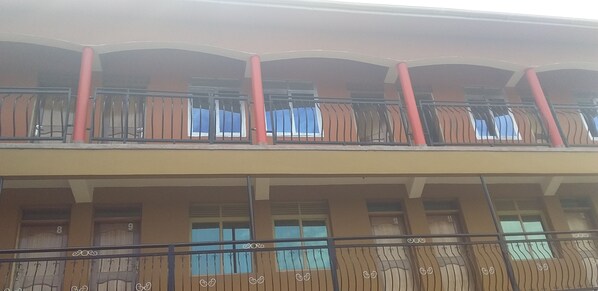 A multi-story building with balconies, large windows, and a red column.