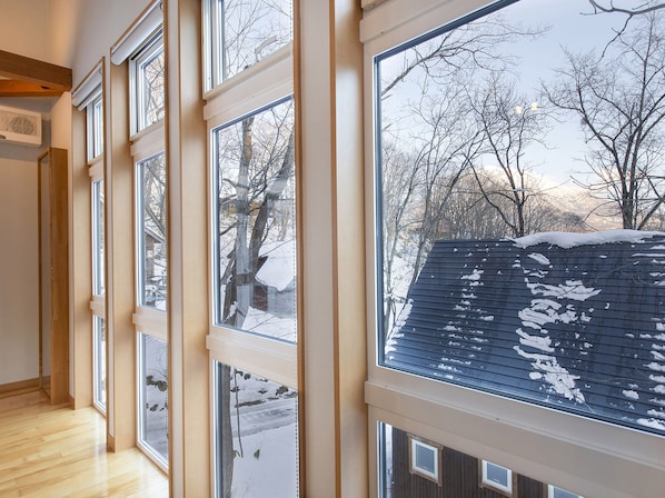 Una habitación con ventanas amplias, piso de madera y vistas a un paisaje nevado.