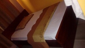 Un lit en bois avec un matelas blanc et une couverture beige.