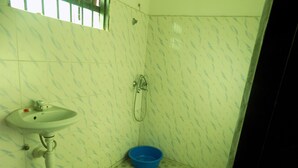 A bathroom with a sink, a shower, and a blue basin on the floor. - Sky Resort (Kitagata)
