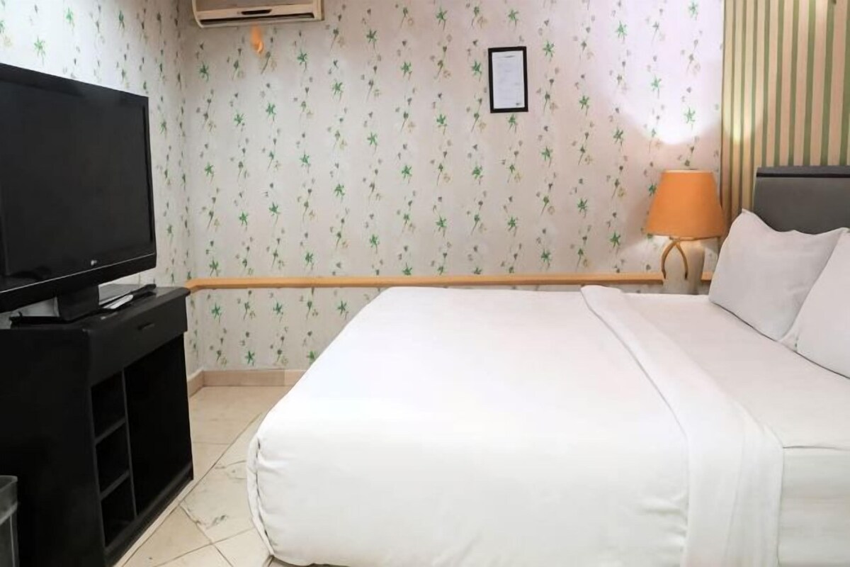 Una habitación de hotel con una cama, un televisor y una lámpara.