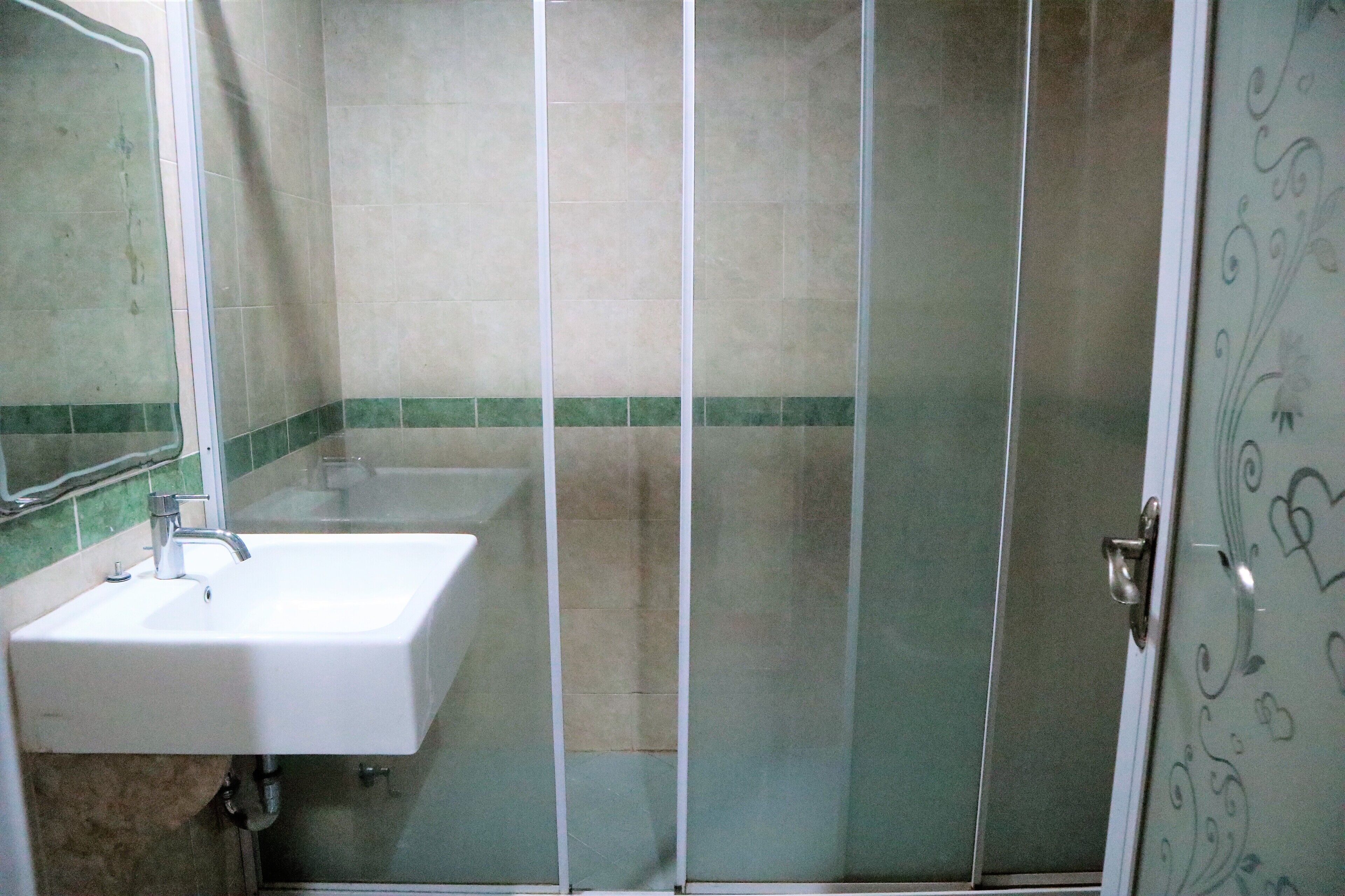 A bathroom with a sink, mirror, and shower enclosure.