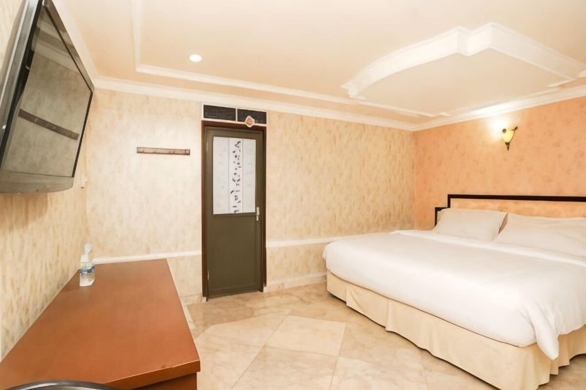 Una habitación de hotel con cama, televisión, escritorio y una puerta con un cartel.