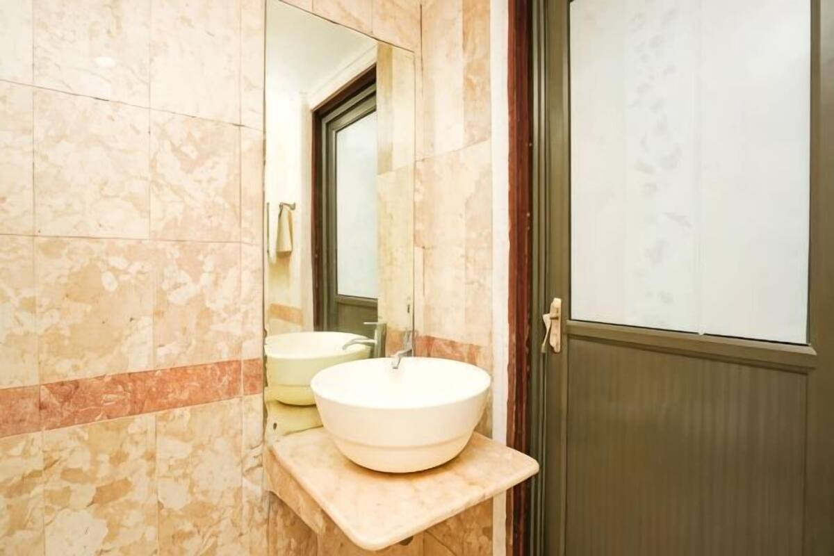 A bathroom with a marble wall, a sink, and a mirror.