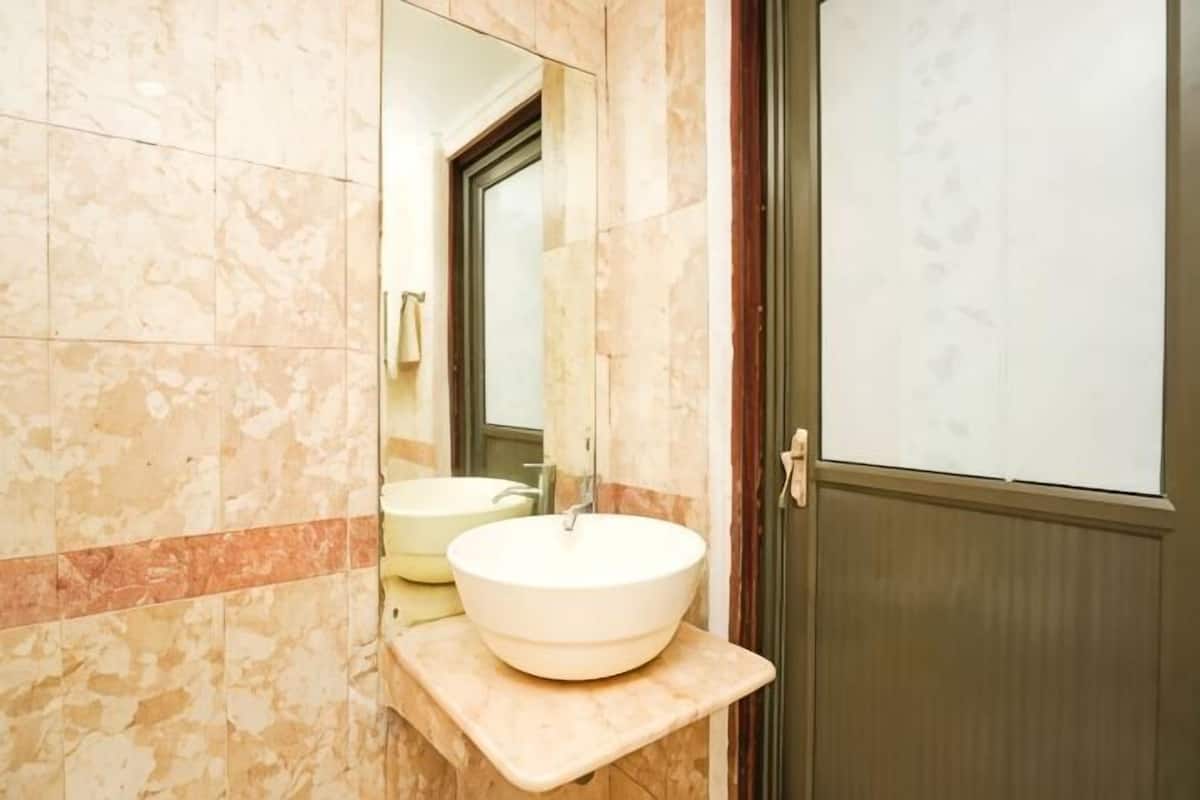 A bathroom with a marble wall, a sink, and a mirror.