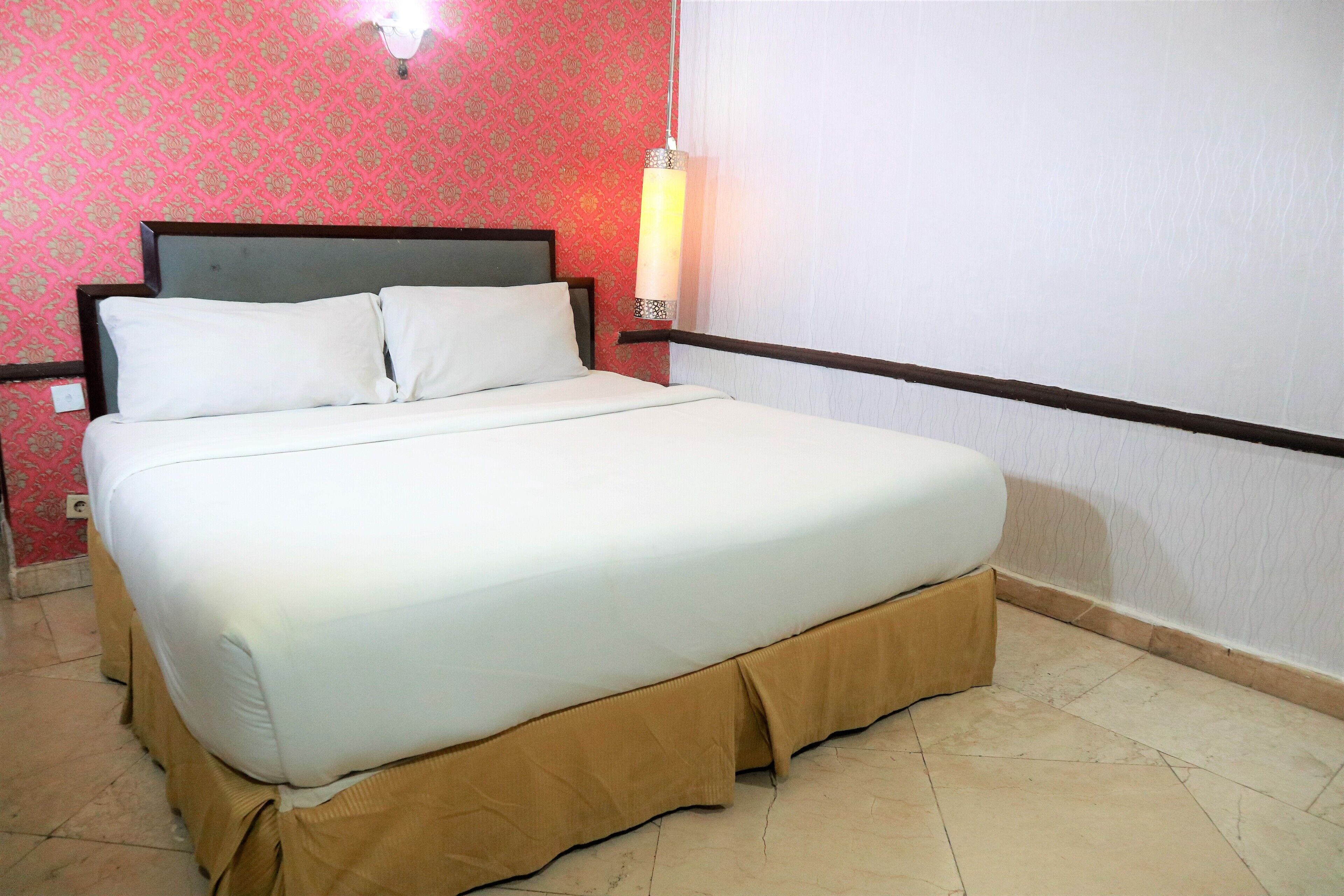 Cama com roupa de cama branca, cabeceira e saia marrom.