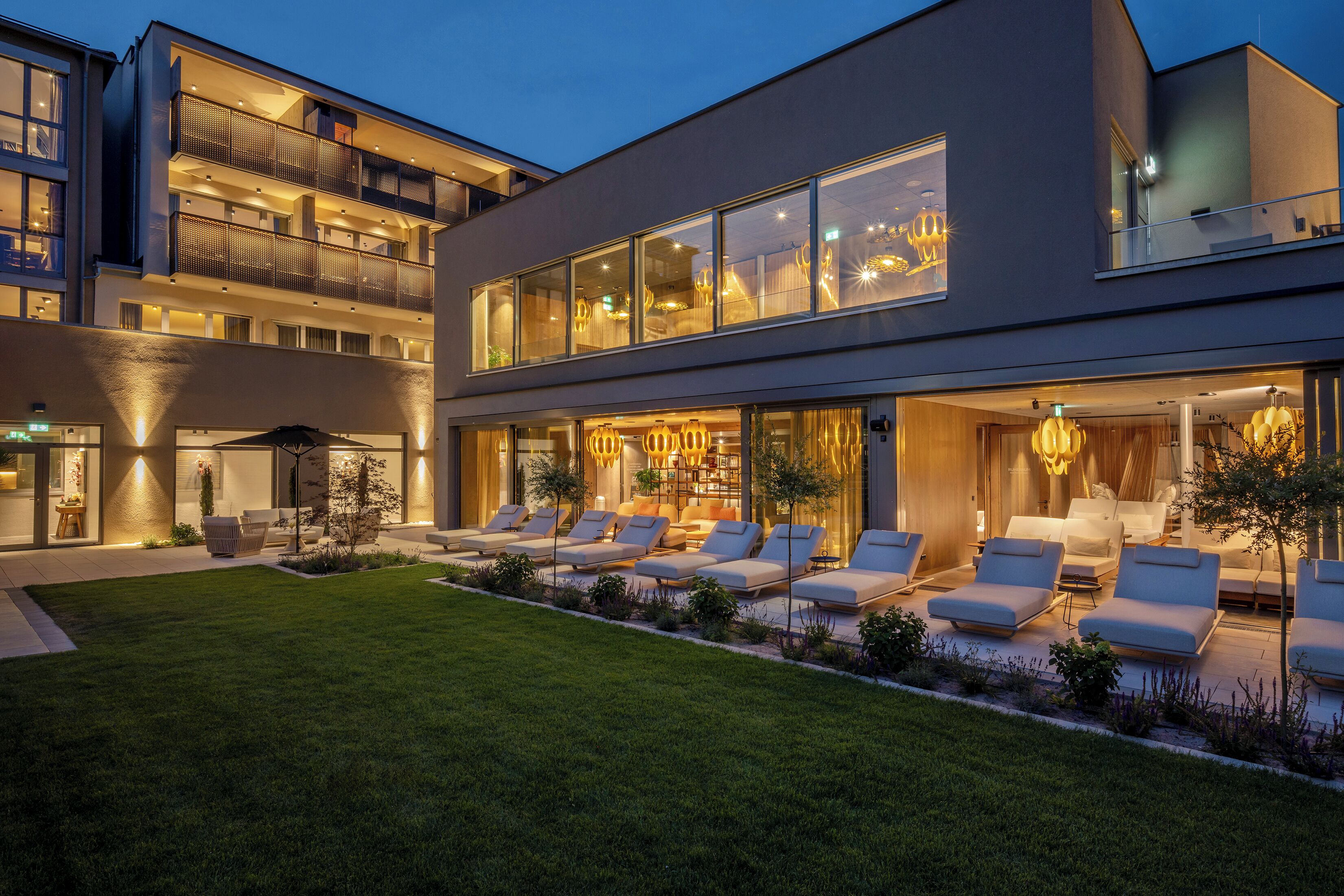 A modern building with a rooftop terrace, large windows, and outdoor seating.