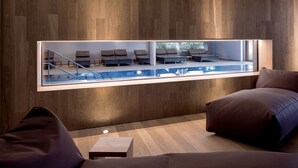 Un área de descanso moderna con vistas a la piscina, paredes de paneles de madera y asientos cómodos.