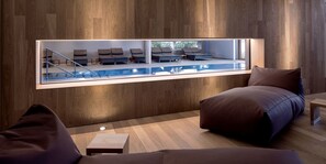 A modern lounge area with a pool view, wooden panel walls, and comfortable seating.