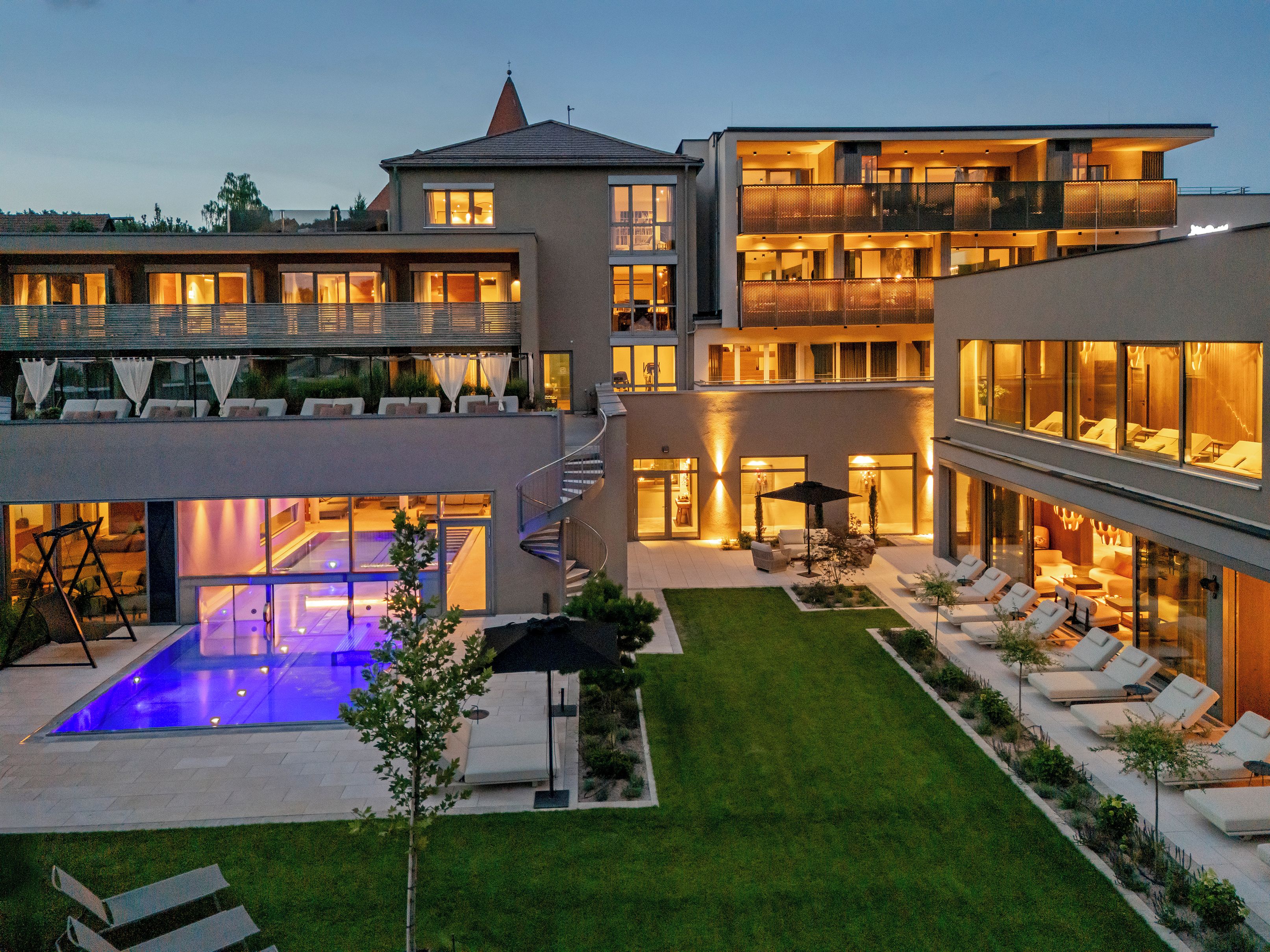 Un hôtel moderne à plusieurs étages, doté d’une piscine sur le toit, d’un espace extérieur aménagé et d’une pelouse bien entretenue.