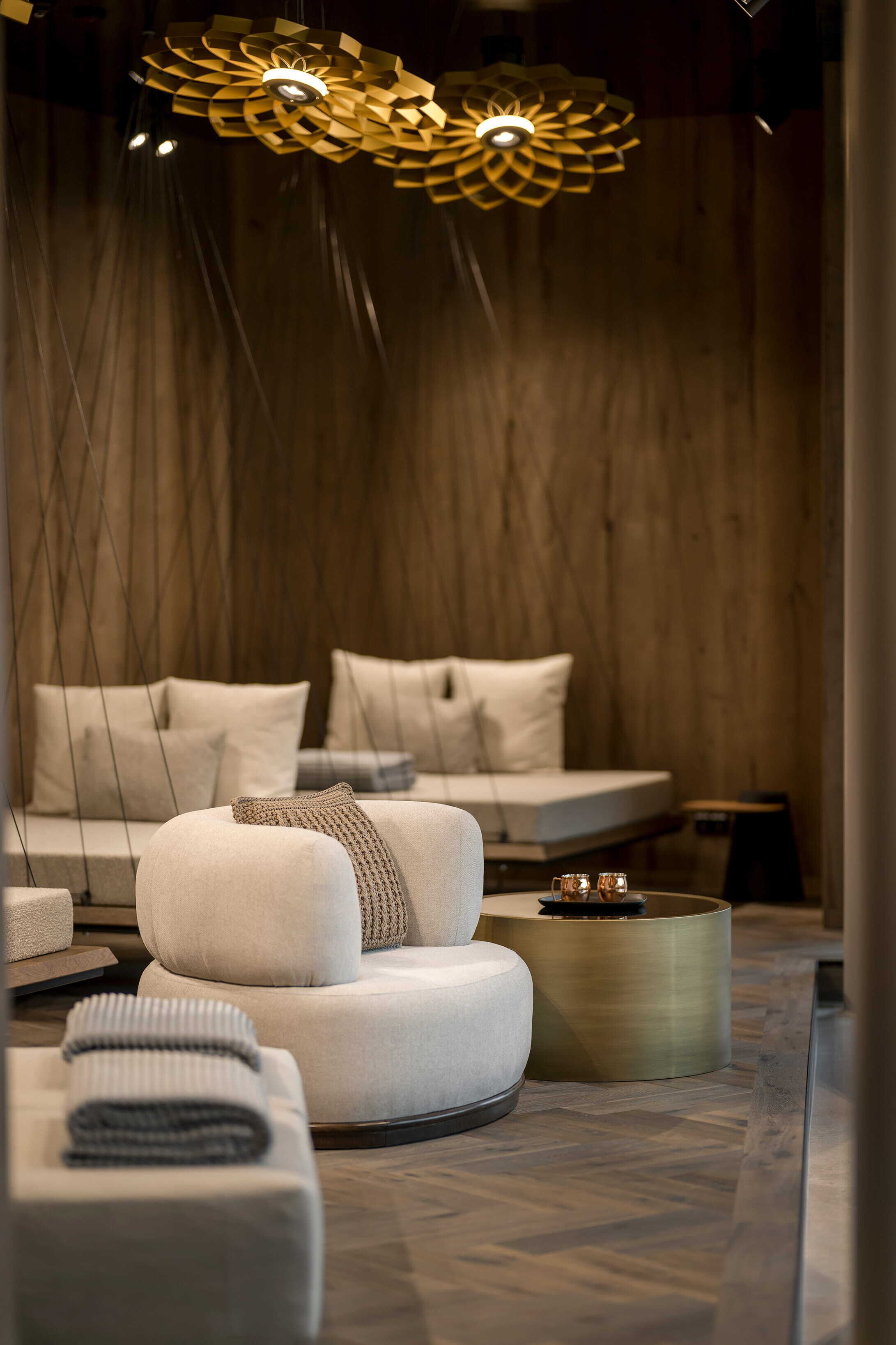 Un'area lounge moderna con un divano, un tavolino rotondo e un originale lampadario a soffitto dalle forme geometriche.