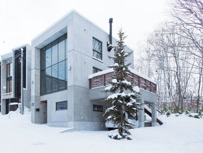A modern building with large windows and a snow-covered tree in front. - Kita Kitsune Chalet (Kutchan)