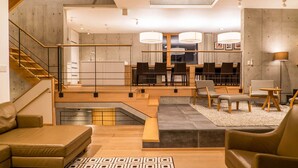 A modern interior with a staircase, seating area, dining space, and a kitchen. - Mizunara Chalet (Kutchan)