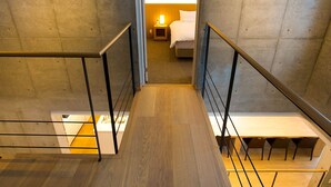 A modern hotel room with a wooden staircase, a bed, and a nightstand. - Mizunara Chalet (Kutchan)