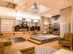 Uma sala de estar moderna com área de jantar, lareira e escada para um andar superior.