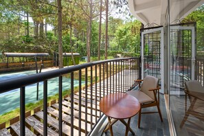 A balcony with wooden railings, a table, and chairs, overlooking a river and a forested area. - Romeo Juliet Dalat Resort (Da Lat)