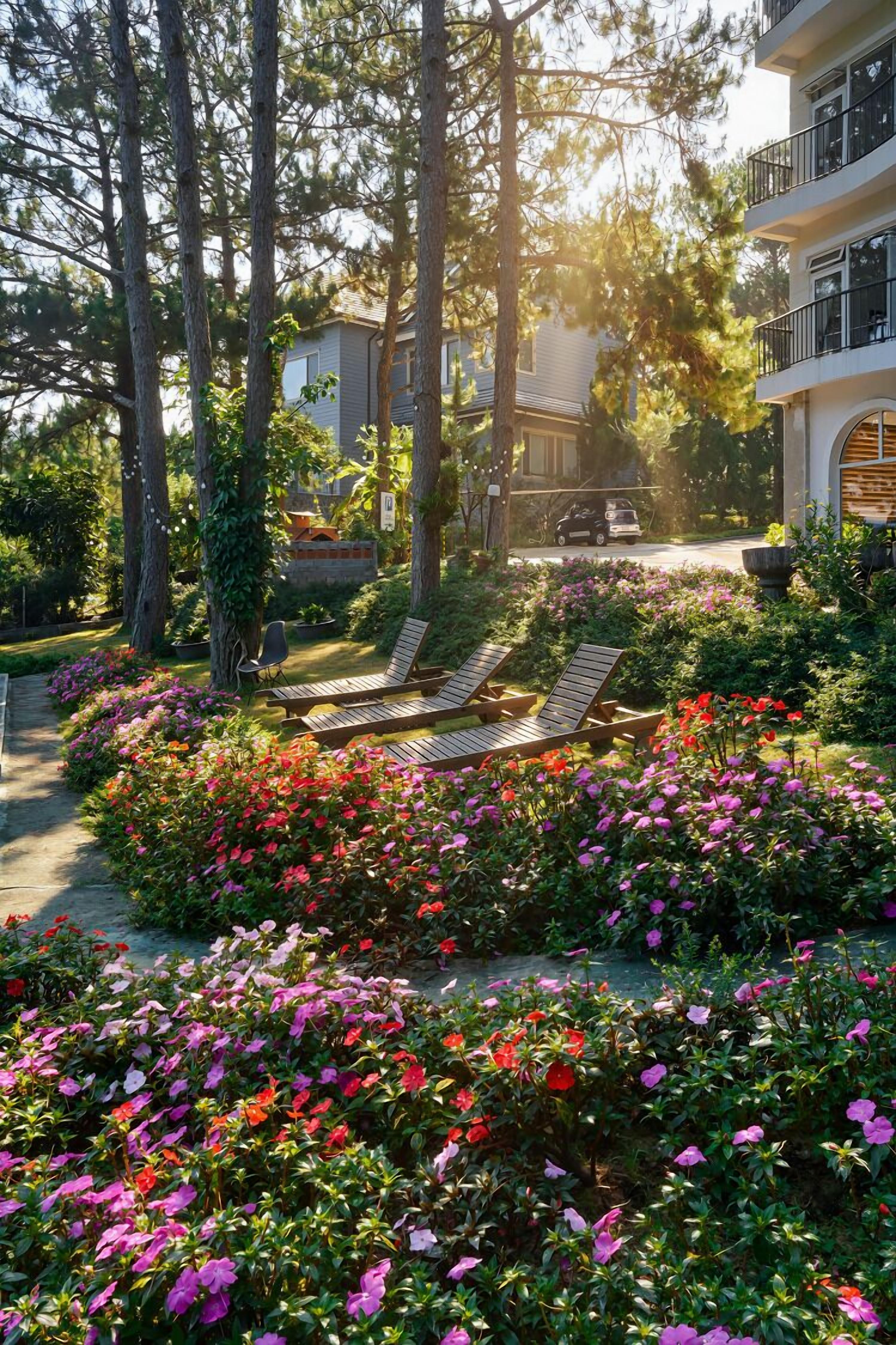Un jardin avec des espaces aménagés où l’on peut profiter du soleil, des arbres et un bâtiment doté de balcons.