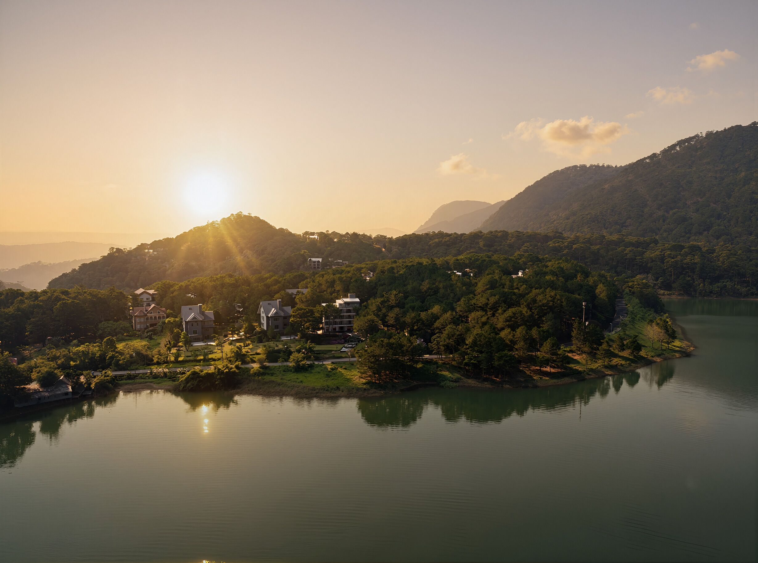 Ein Seeufergrundstück mit mehreren Gebäuden, einem bewaldeten Hügel und freiem Blick auf den See.