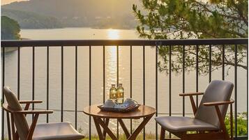 A balcony with two chairs, a small table, and a tray with bottles and glasses.