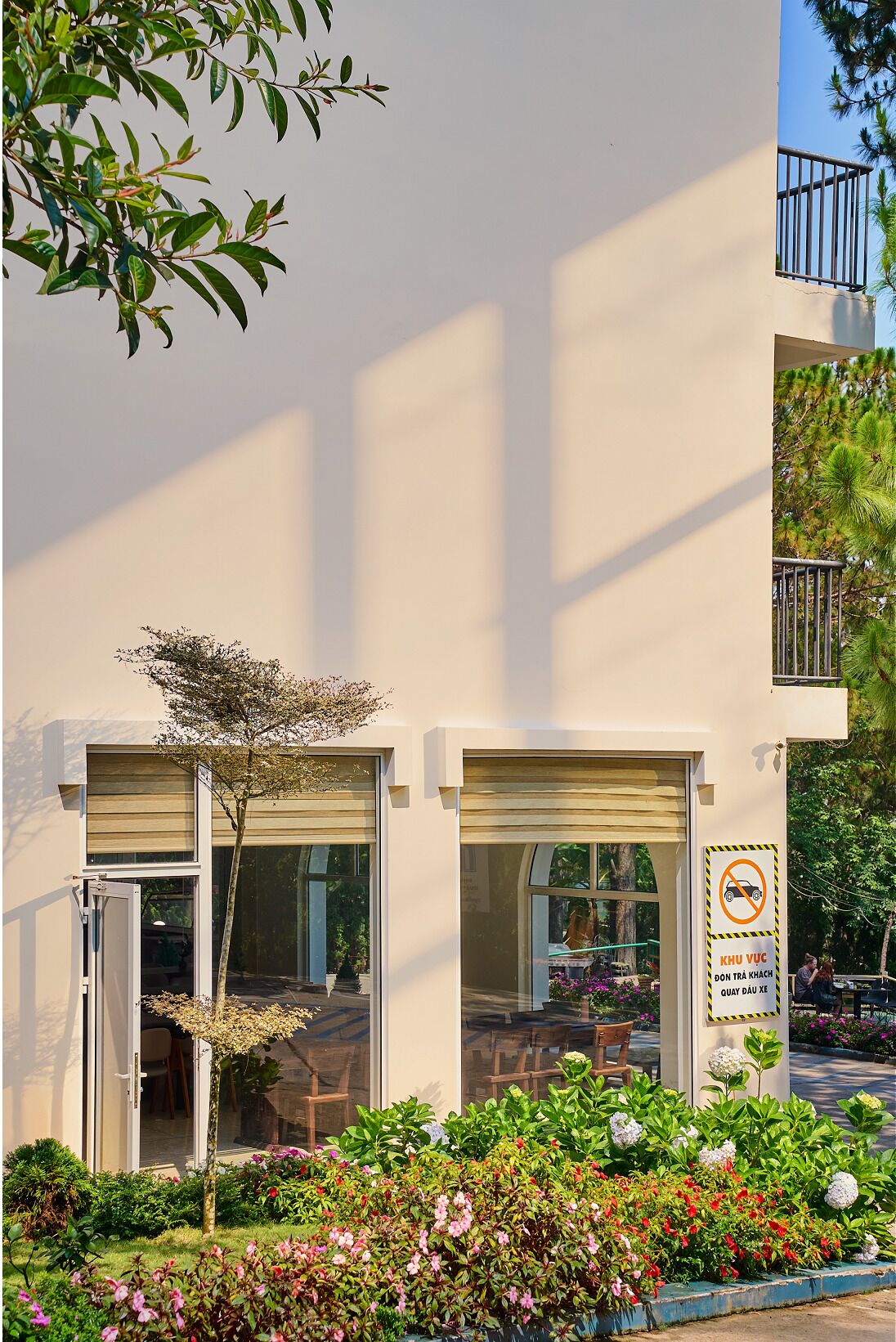 Un edificio con dos puertas de vidrio, un balcón y un letrero que indica prohibido estacionar.