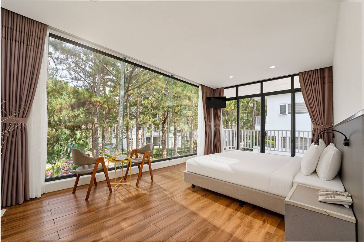 A modern room with a large window, a sofa, a small table, and a TV mounted on the wall.