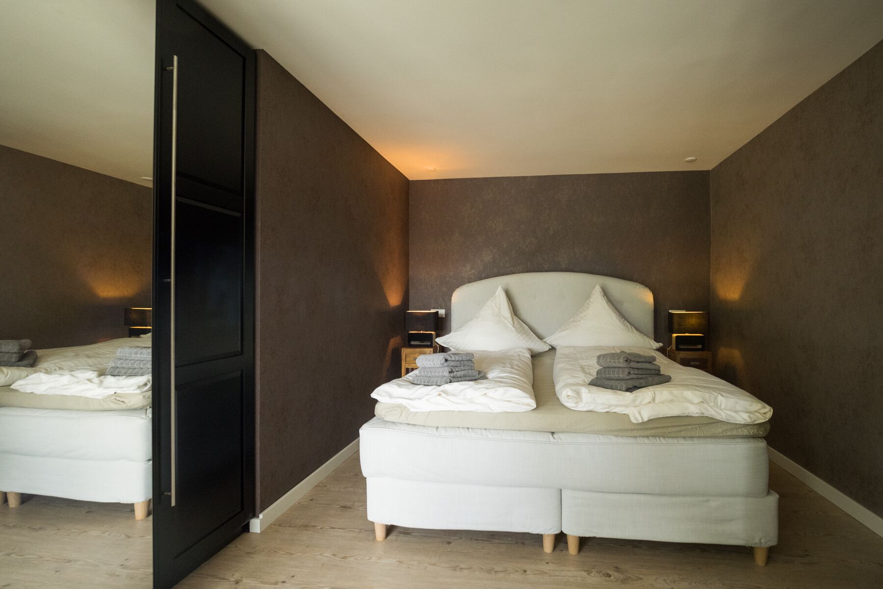 Quarto moderno com uma cama grande, luminárias de cabeceira e um guarda-roupa.