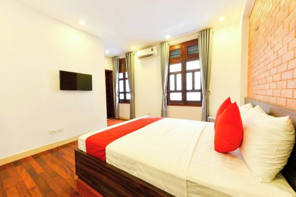Une chambre d’hôtel avec un lit, un téléviseur à écran plat et un mur en briques.