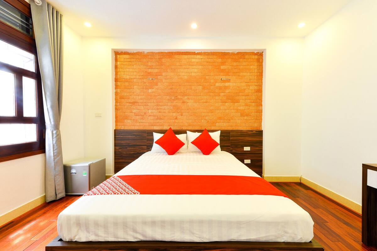 Een hotelkamer met een groot bed, een accentmuur van baksteen en een kleine verwarming.