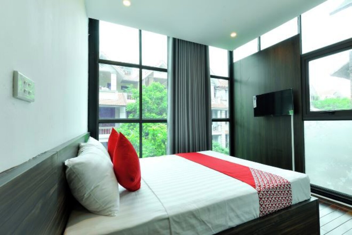 Une chambre d’hôtel moderne avec un grand lit, un téléviseur fixé au mur et une vue sur la verdure.
