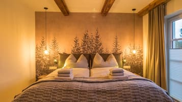 Quarto com cama grande, vigas de madeira no teto e janela com cortinas.