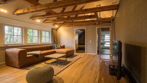 A spacious living room with a wooden ceiling, a large TV, a sofa, and a coffee table. - Kajüte Sieben 2 (St. Peter-Ording)