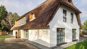 A house with a steeply pitched roof, white exterior walls, and large windows. - Kajüte Sieben 2 (St. Peter-Ording)