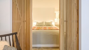 Quarto com cama, almofadas e moldura de porta de madeira.