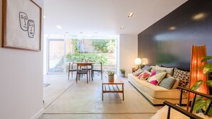 Uma sala de estar moderna com sofá, mesa de centro e área de jantar com cadeiras e mesa.