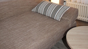A modern living room with a sofa, a round coffee table, and a floor lamp. - Hotel Kromberg (Remscheid)