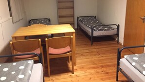 A small room with a wooden table and chairs, two single beds with polka dot bedding, a wooden floor, and a door. - Pfaffenhofen Monteurzimmer (Pfaffenhofen)