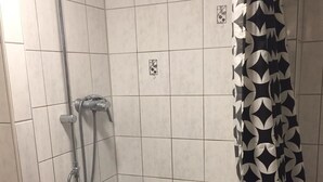 A shower area with a black and white patterned shower curtain, tiled walls, and a handheld showerhead. - Pfaffenhofen Monteurzimmer (Pfaffenhofen)