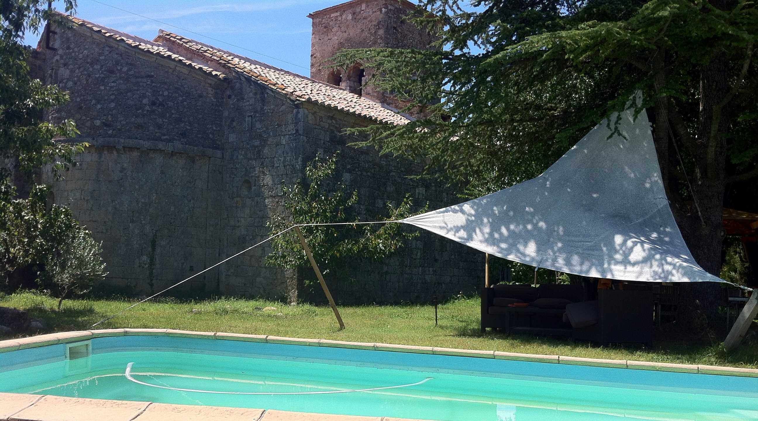 Ein Schwimmbecken mit einem dahinterliegenden Steinhaus.