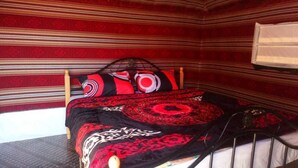 A room with a bed, striped wallpaper, and a red and black patterned bedspread. - Bedouin Experience Camp (Wadi Rum)