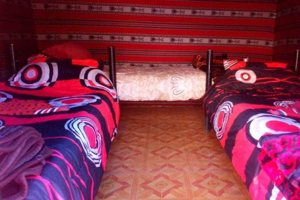 A room with two beds, each with patterned blankets, and a patterned carpet.