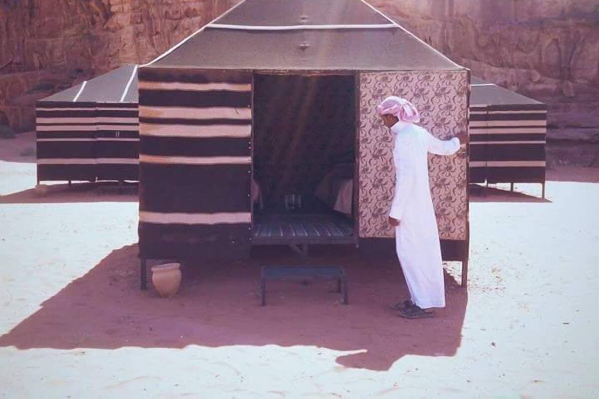 A traditional tent-like structure with a flat roof, a bench, and a pot outside.