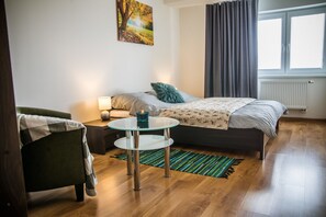 A modern bedroom with a bed, a chair, a small table, and a window with curtains. - Apartment Eric 9D High Tatras (Velky Slavkov)