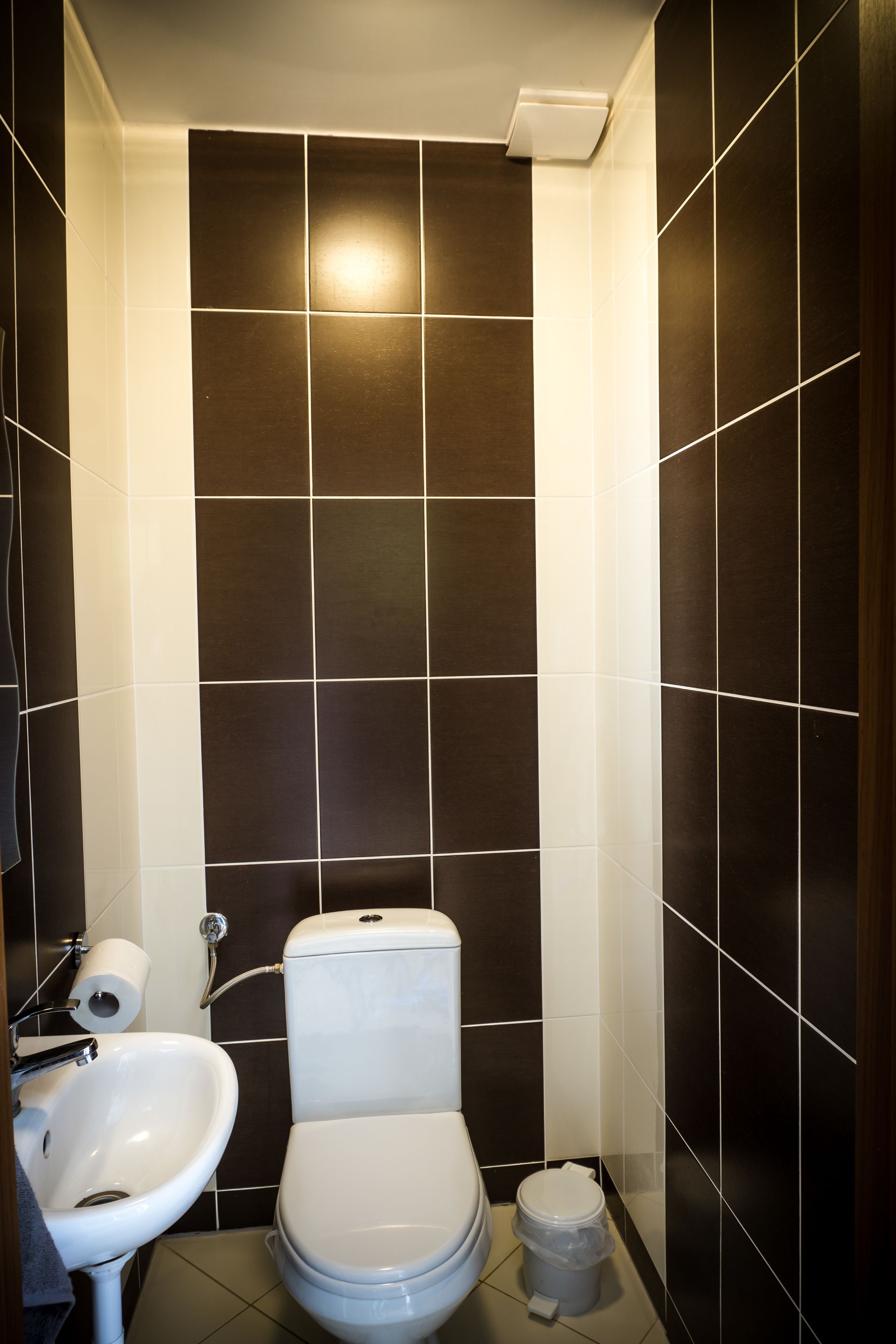 Un baño con inodoro, lavabo y cubo de basura.